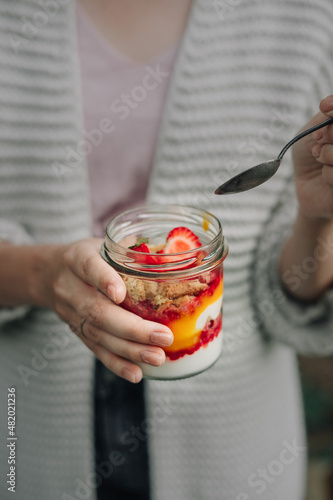 Woman holding glass jar with a plant based dessert. Vegan yogurt.
