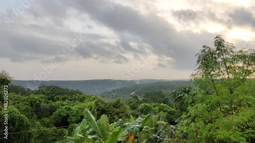 Time lapse view of moving clouds over the green landscape at the evening 