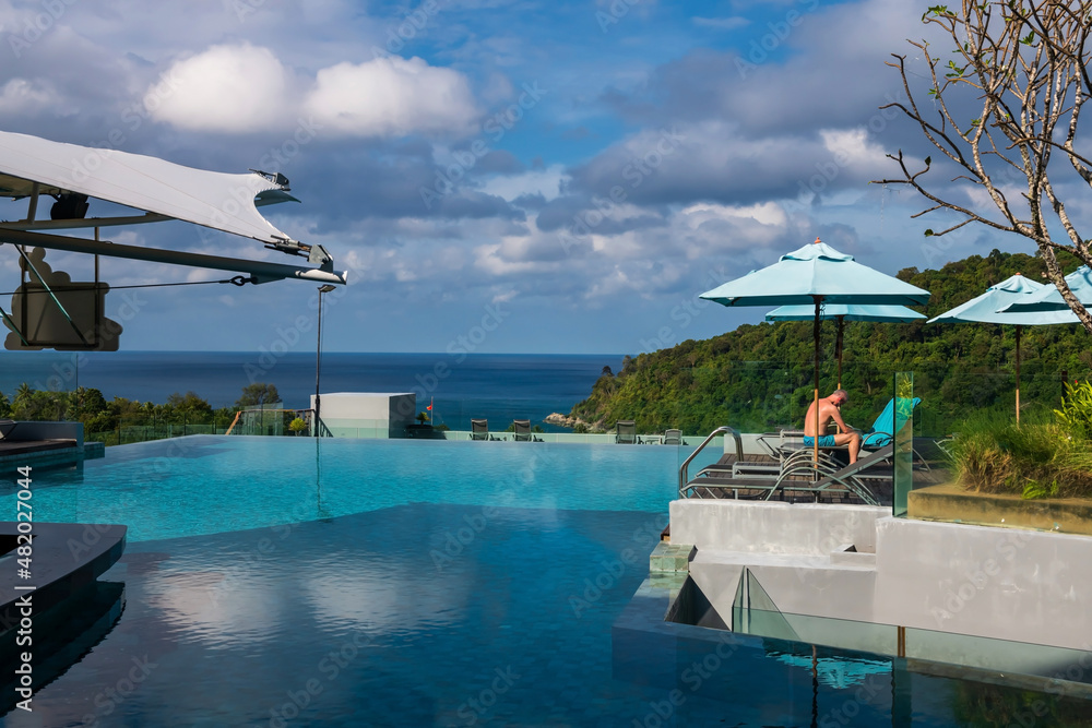 Fototapeta premium Foreign man get tan by pool with sea view, Phuket