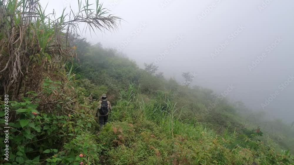 A Man Hiking on the Mountain that covered in fog A Man Hiking on the Mountain that covered in fog
