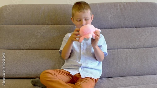 the boy is sitting on the sofa and playing with a toy octopus