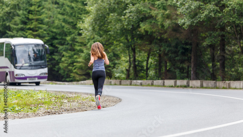 Runner woman running on the mountain road through the forest. Female sport girl training outdoors for marathon © skumer
