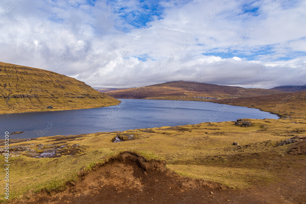 Woman on a bench looking at Leitisvatn Lake, Faroe Islands.