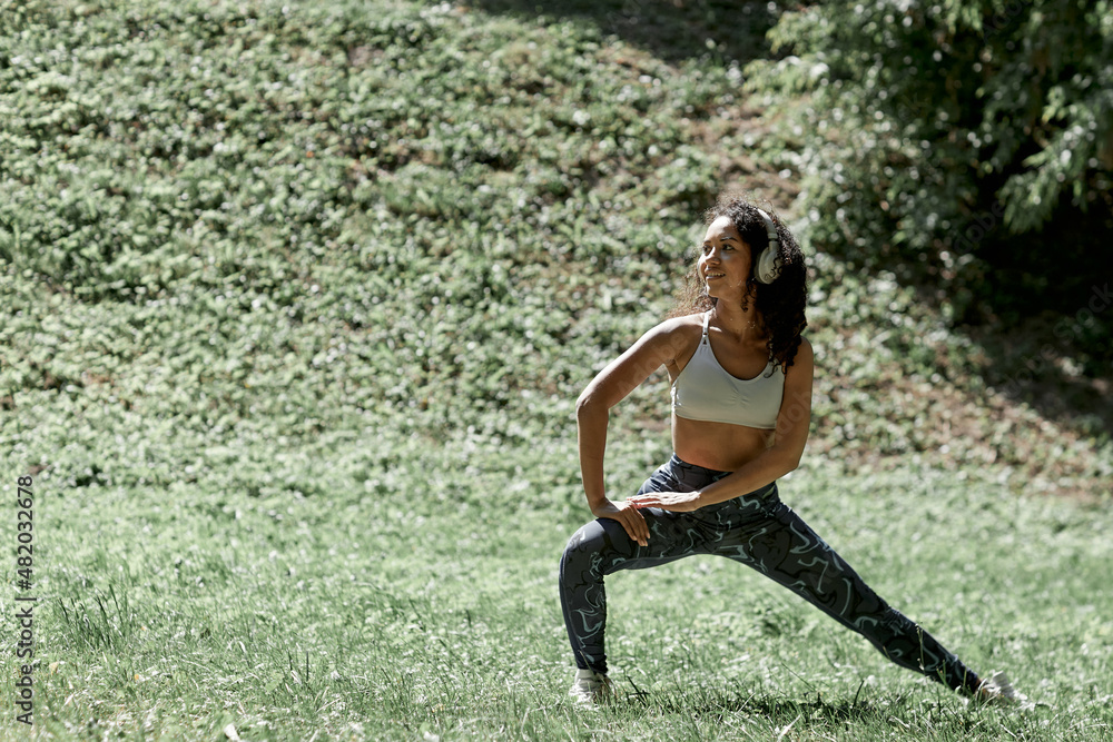 Beautiful girl doing yoga on green grass in park at summer morning