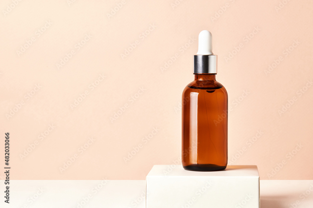 A glass bottle with aromatic oil or serum on a  white podium. Natural Organic Spa Cosmetic concept. 