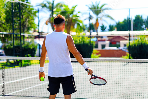 Senior caucasian man playing tennis on court holding tennis racket day light outdoors on fresh air © yurakrasil