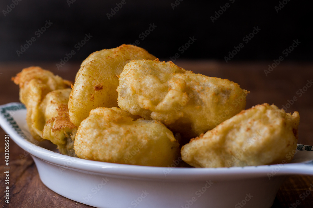 Fried cod served in serving dish on wooden background Fried cod served in serving dish on wooden background
