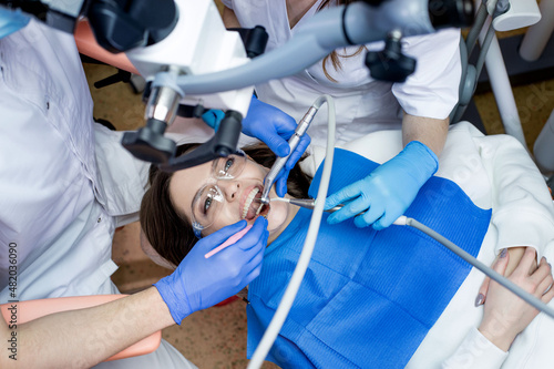 Fototapeta Naklejka Na Ścianę i Meble -  Dentist with assistant under microscope treats the patient's teeth. Modern progressive dentistry