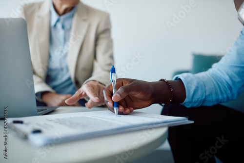 Close-up of black man signing contract with insurance agent in the office. photo