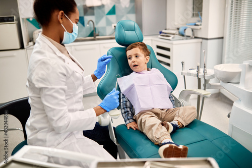 Small boy talks to his dentist during dental exam at dentist s office.