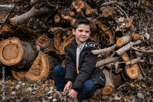Foto A young kid sitting on the logs and posing his best and smiling and trying to be