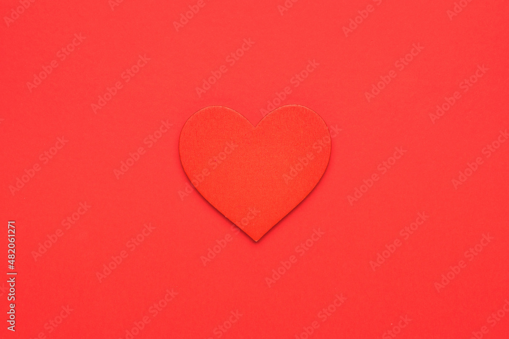 Red wooden heart on a bright red background. The concept of falling in love and Valentine's day. Minimalism.
