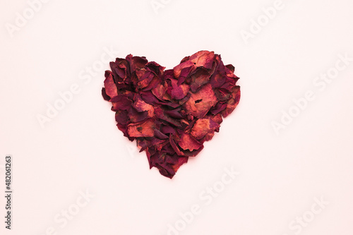 A beautiful heart made of dried rose petals on a pastel background. The concept of a romantic relationship.