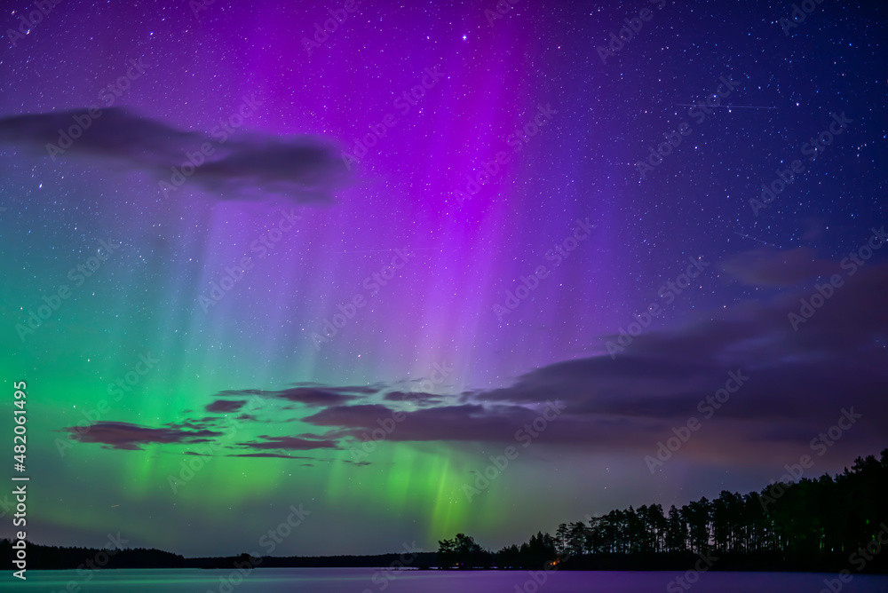 Northern lights dancing over calm lake in Farnebofjarden national park in north of sweden.