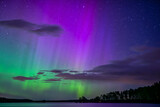 Northern lights dancing over calm lake in Farnebofjarden national park in north of sweden.