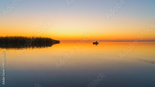 Orange sunset on a quiet lake  sunset reflected in calm water