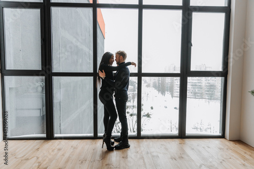 Couple in love tenderly hugs in a cozy home environment and panorama window
