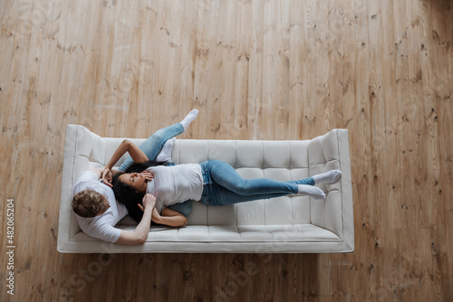 View from above affectionate young multiracial couple cuddling on sofa