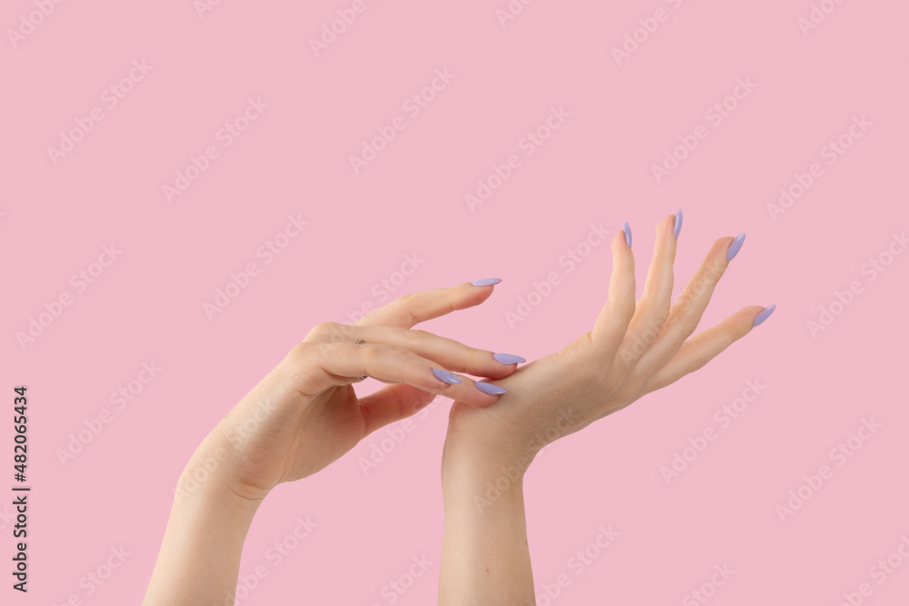 Hands of a beautiful well-groomed with feminine violet lavender nails gel polish on a pink background. Manicure, pedicure beauty salon concept.