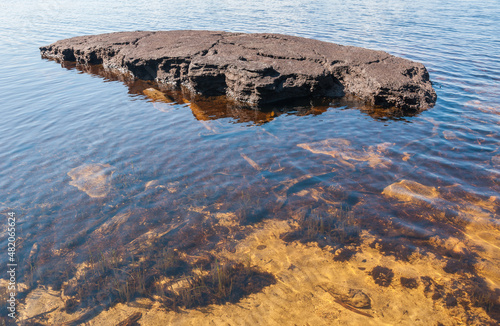 Large flat stone in lake in summer, Karelia, Russia