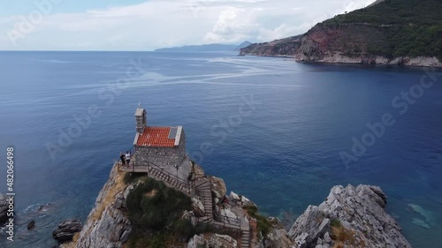 Drone aerial view of Christian Church of Holy Sunday on small island Katic  in Petrovac, Montenegro during summer sunset. Epic religious and tourist attraction accessible by boat. photo