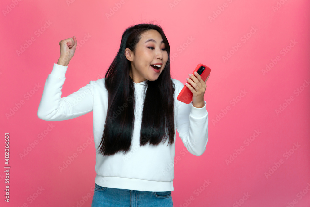 Excited delighted asian girl hold phone feeling euphoric from mobile online game win celebrating good news Excited delighted asian girl hold phone feeling euphoric from mobile online game win celebrating good news