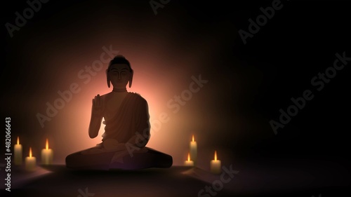 Silhouette of the Buddha in the lotus position against the background of light and candles