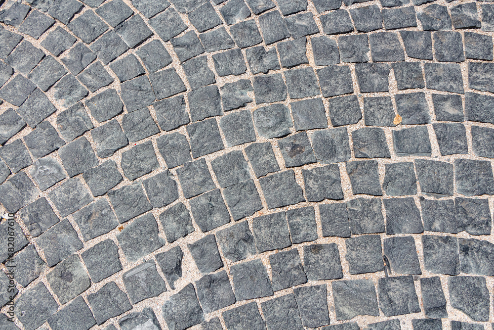 Fototapeta premium Beautiful texture of path of gray square stones with sand is in the park
