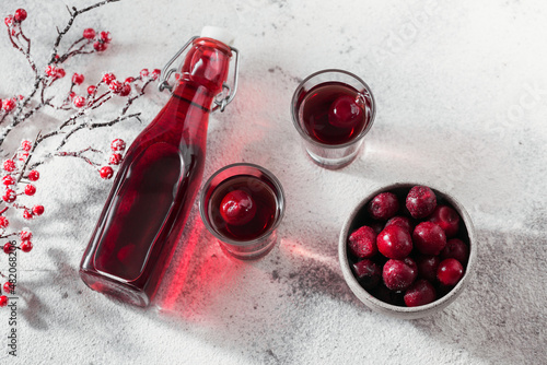 Homemade infused vodka, tincture or liqueur of red cherry on white background. Berry alcoholic drinks concept. photo