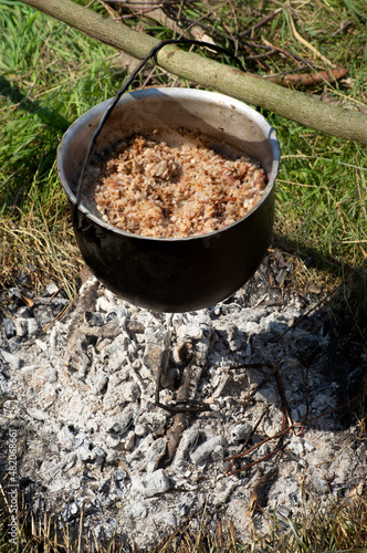 cooking porridge in a special bowl on an open fire for a group of tourists