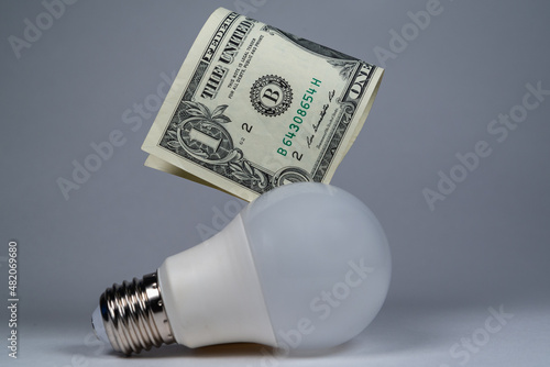 Light bulb and money, dollars. Saving electricity, rising prices.