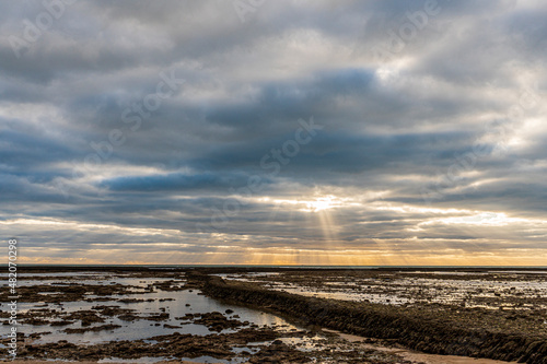 Hermosa panorámica del atardecer con los reflejos del sol atravesando las nubes y cayendo sobre el mar en la playa de Chipiona (Cádiz)