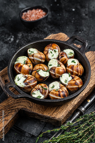 Delicatessen food - Bourgogne Escargot Snails with garlic butter in a pan. Black background. Top view