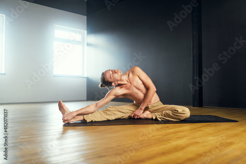 Fotografi The yogi man do janu shirshasana. Yoga practice in the studio.