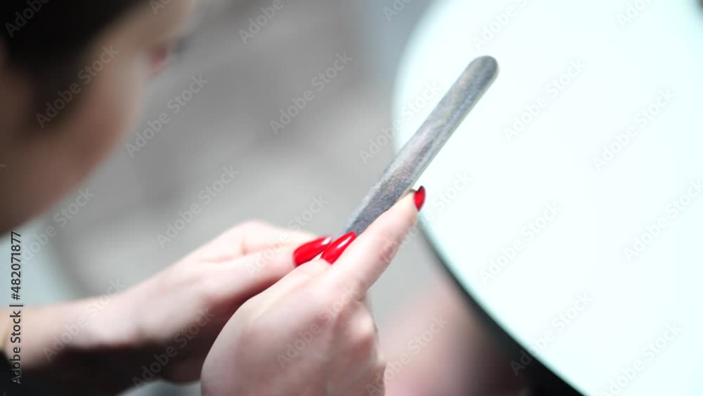 Girl corrects nails after manicure with a nail file. Girl corrects nails after manicure with a nail file.