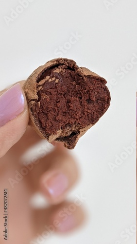 a part of chocolate truffle homemade candy  in a woman hand on the white background