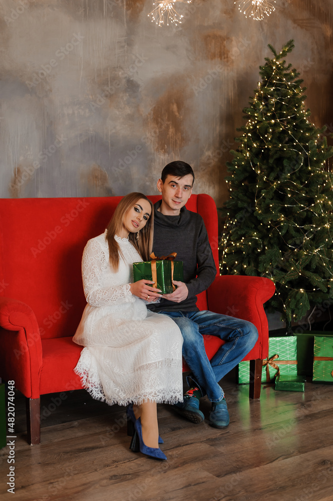 Obraz premium Man and woman sitting on a red sofa and holding a gift