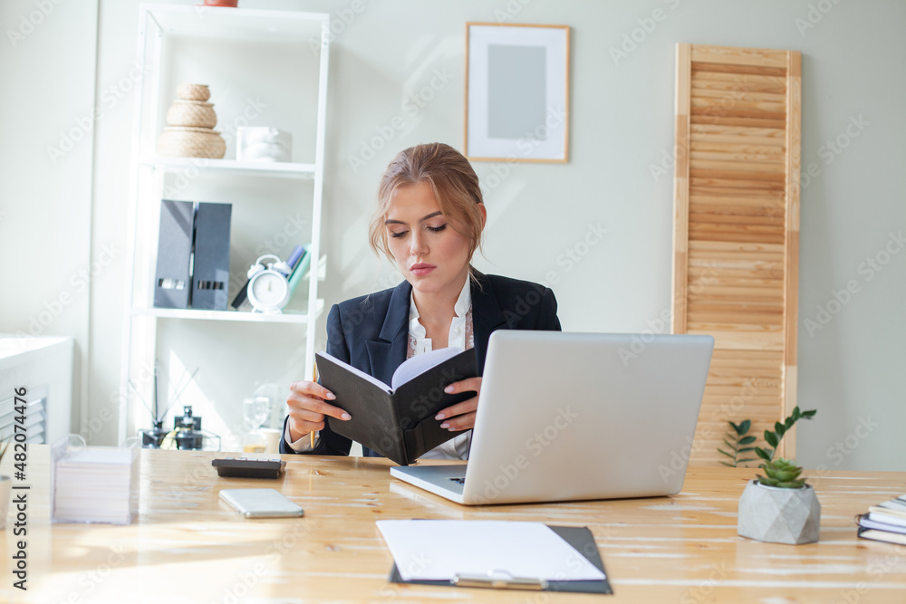 Serious businesswoman looking at her notebook in office Serious businesswoman looking at her notebook in office