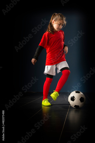 The girl football player is having fun with the ball indoors