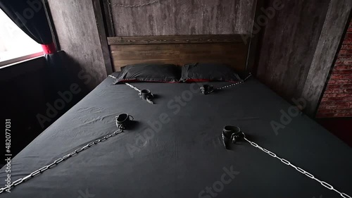 BDSM Leather handcuffs for role-playing games on a gray sheet. Bondage for carnal pleasures. Domination and submission. Departing camera. No people photo