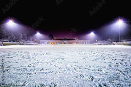 snowy soccer stadium, football stadium covered with snow sport field in the dark
