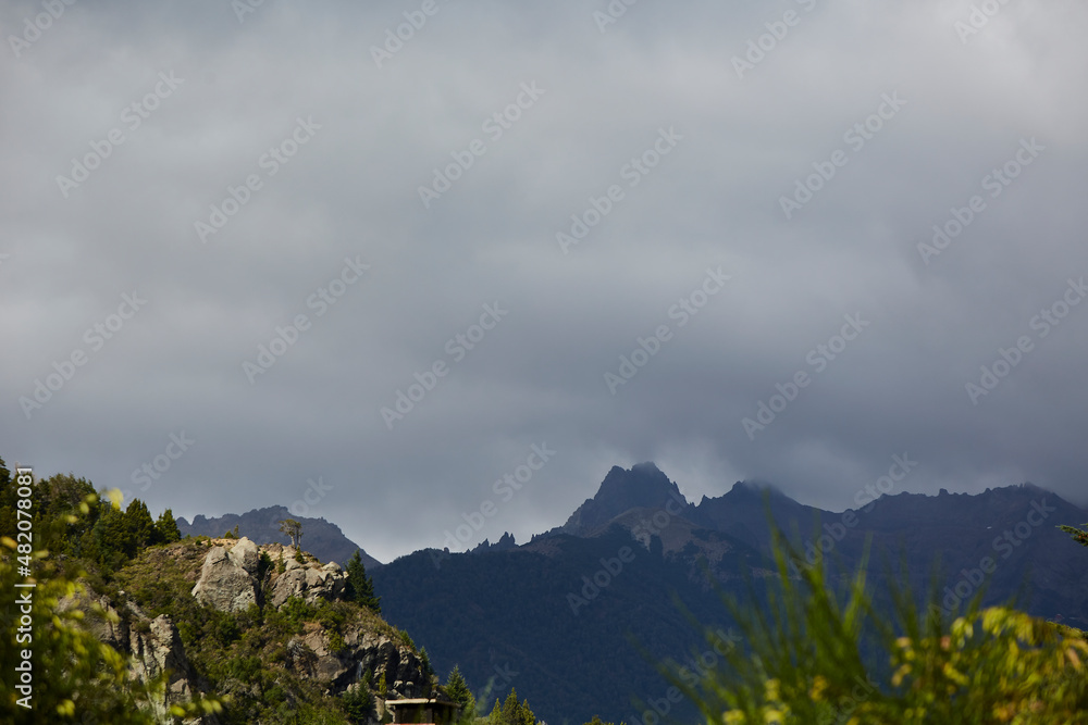 Mountain summit, peak or summit of a mountain in the Argentine Patagonia. Mountain of the Andean Cordillera. Vegetation in front and sky with many clouds.