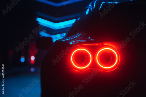 Supercar led taillight at the night city street, rear view