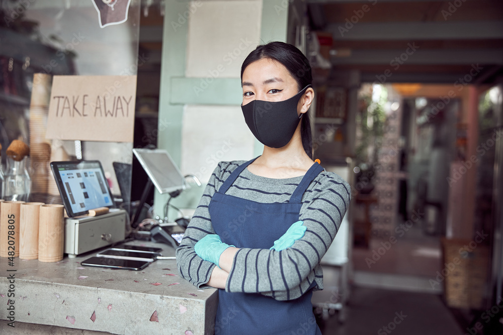 Fototapeta premium Portrait of young woman in face mask working in cafe