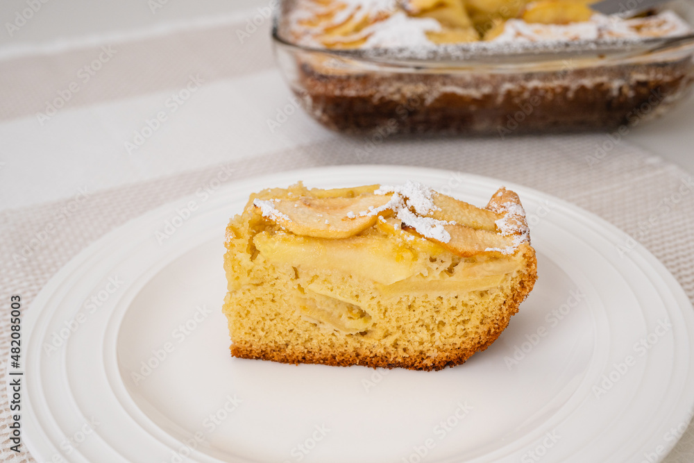 Slice of apple cake with biscuit base close up on a white plate. Fresh baked delicious homemade apple cake, breakfast, dessert Slice of apple cake with biscuit base close up on a white plate. Fresh baked delicious homemade apple cake, breakfast, dessert