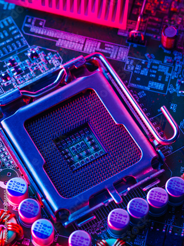 The desktop of the processor lies with the contacts up on the motherboard of a personal computer. Illuminated with blue neon light. Technological background. Computer parts, repair, new technologies.