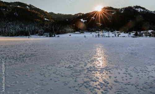 frozen alpine lake Weissensee at sunset 