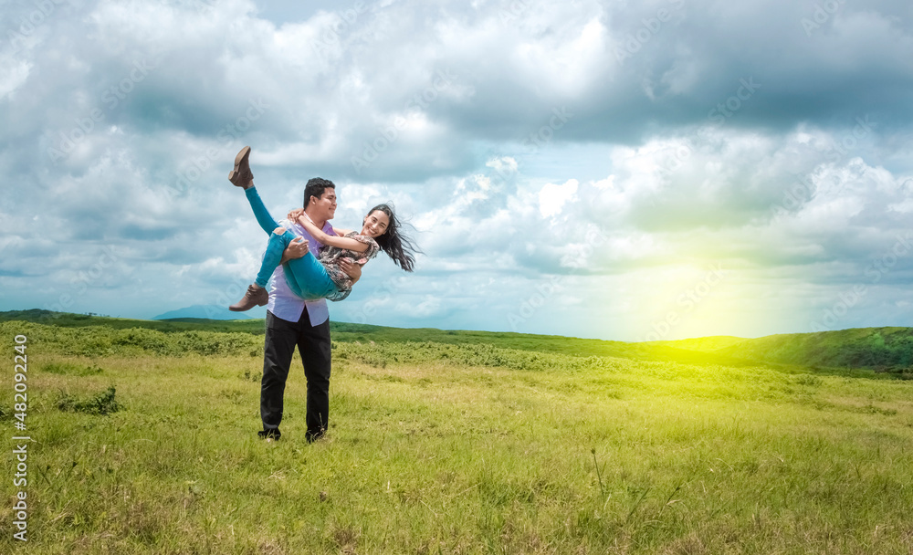 Happy couple in love in the field, happy man carrying his girlfriend in the field Happy couple in love in the field, happy man carrying his girlfriend in the field