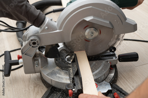Miter saw in the process of sawing off a wooden part.