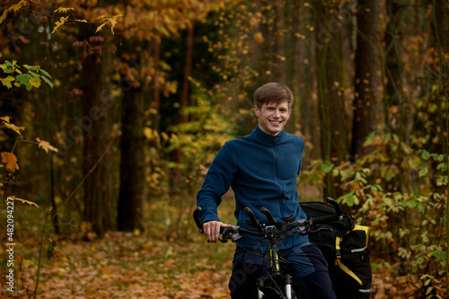 Smiling handsome caucasian bicyclist in autumn forest